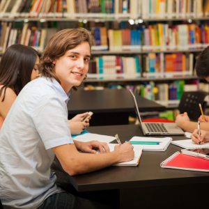 Doing homework in the library Group of college students working together in the school library